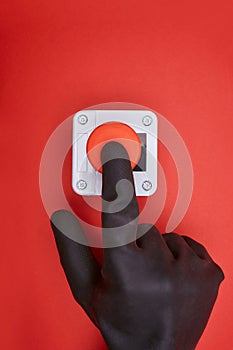 The hand in black vinyl glove, which pushes the emergency button at the red background