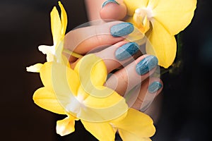 Hand with blue glitter nails with flower