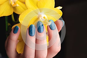 Hand with blue glitter nails with flower