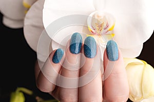 Hand with blue glitter nails with flower