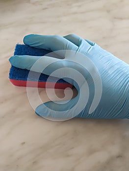 Hand in blue glove holding dish washing sponge make cleaning