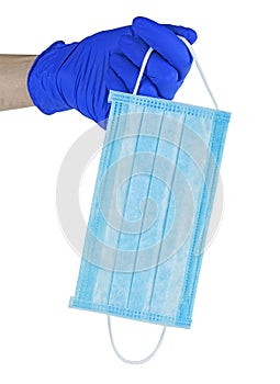 Hand in blue glove holds a blue medical face mask against viruses and bacteria on white background. Protective medical tool