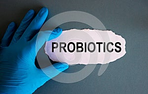 Hand in blue glove with white small paper. Concept word probiotics