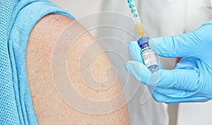 Hand in blue gloves holding syringe and chloroquine phosphate generic name, sticker own design dummy data, about to inject it to