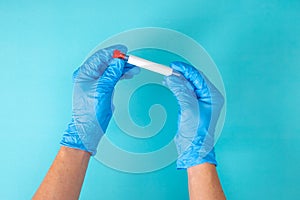 Hand in blue gloves holding a test tube