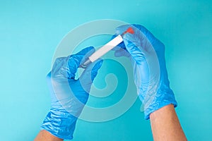 Hand in blue gloves holding a test tube