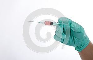 Hand in blue green glove holding syringe