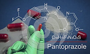 Hand with blue latex glove holds a capsule of metamizol, chemical composition