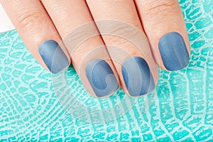 Hand with blue matte manicured nails