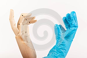 Hand in blue medical glove and hand of wooden doll. Hands concept. Hope. Help. Concept