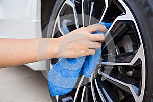 Hand with blue microfiber cloth cleaning car