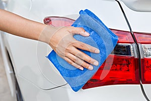 Hand with blue microfiber cloth cleaning taillight