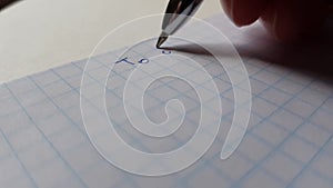 A hand with a blue pen writes on checkered paper to do