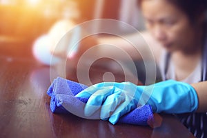 Hand in blue rubber glove holding blue microfiber cleaning cloth and spray bottle with sterilizing solution make cleaning