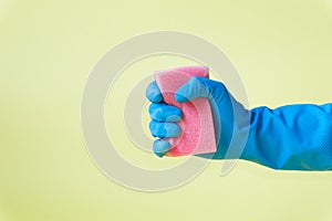 Hand in a blue rubber glove holds red sponge.