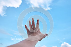 Hand with blue sky and cloud in background.