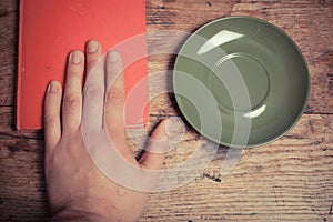 Hand with book and saucer