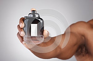 Hand, bottle and cologne with a man in studio on a gray background holding a perfume fragrance product. Luxury scent