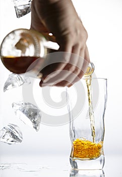 Hand with a bottle filling a transparent glass with alcohol