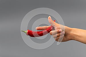 Hand with bottle of pepper spray on gray background.