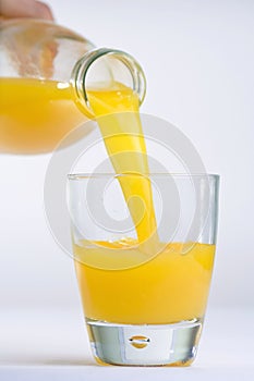 Hand, Bottle pouring Orange juice over glass