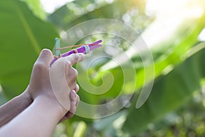 Hand of boy holding a self-made gun toy play made from colorful popsicle sticks with rubber band.