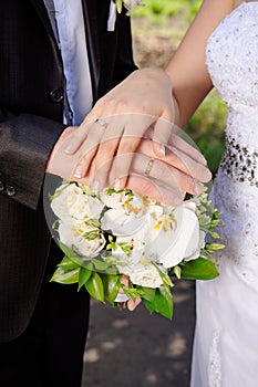 Hand the bride and groom with rings on wedding bouquet