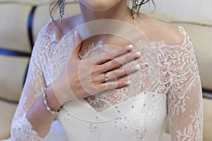 Bride holds her hand with an engagement ring on chest