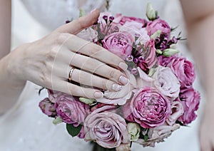 Hand of the bride with a ring holds a wedding bouquet. Wedding decorations. Close-up. The bride`s bouquet