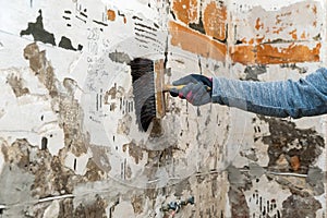 Hand with brush applying primer on the wall