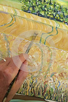 Hand and brush of an artist painting a landscape