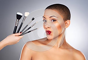 Hand with brush, makeup and girl in portrait by studio background for wellness, beauty and cosmetics with pout