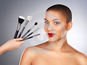 Hand with brush, makeup and woman in portrait by studio background for wellness, beauty and cosmetics with smile