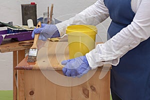 Hand with a brush varnishing a pine wood furniture