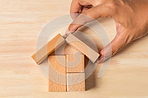 Hand building house real estate with wooden blocks