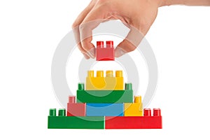 Hand building up a wall by stacking up lego, business conception photo