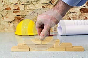 Hand building a wall in little wooden blocks