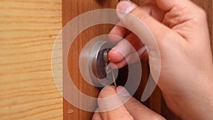 Hand of burglar opens lock of wooden door with a master key, security is caught,