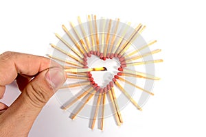 Hand with burning match with shape of heart matches isolated on white background