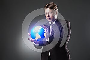 Hand of Business Man Hold Earth Globe on dark