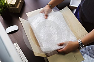 Hand of business man holding Bubble Wrap or Bubble sheet for Wrapping near parcel box on black desk in home office