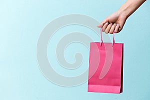 Hand of business woman hold pink shopping bag on blue concrete background