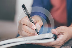 Hand business woman are sitting using pen writing Record Lecture note pad into the book in coffee shop