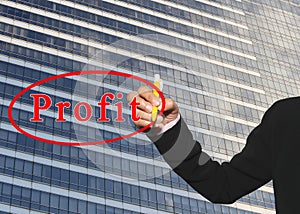 hand of business woman using yellow pen write profit text on Glass wall of tall building of background.