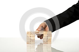 Hand of a businessman assembling a bridge of wooden pegs