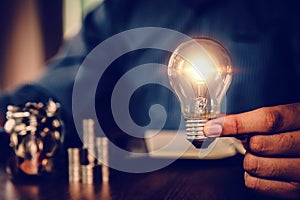 Hand businessman choose light bulb with bright and coin stack in graph concept of creative financial planning idea goal to growth