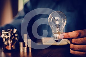 Hand businessman choose light bulb with coin stack in graph concept of creative financial planning idea goal to growth and startup