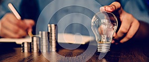 Hand businessman choose light bulb with coin stack in graph concept of creative financial planning idea and startup marketing