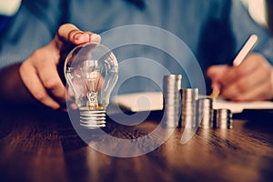 Hand businessman choose light bulb with coin stack in graph concept of creative financial planning idea and startup marketing