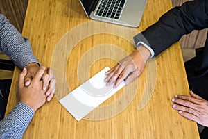 Hand of a businessman hands over a resignation letter final remuneration to executive boss on a wooden table to his boss Change of